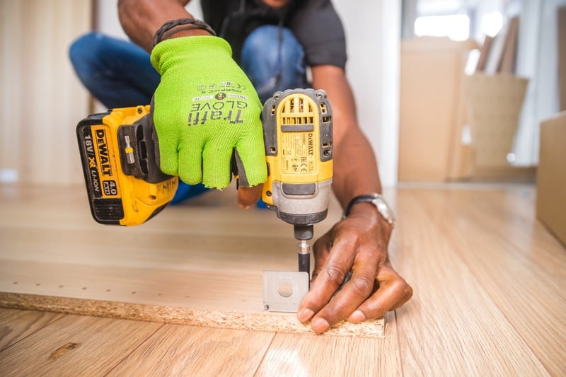 A trades professional using a drill to fasten a bracket to wood - Corporate Transparency Act